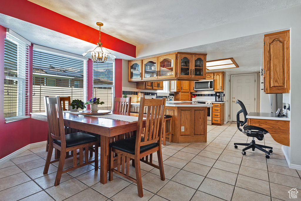 Dining room featuring light tile patterned floors, baseboards, and a chandelier