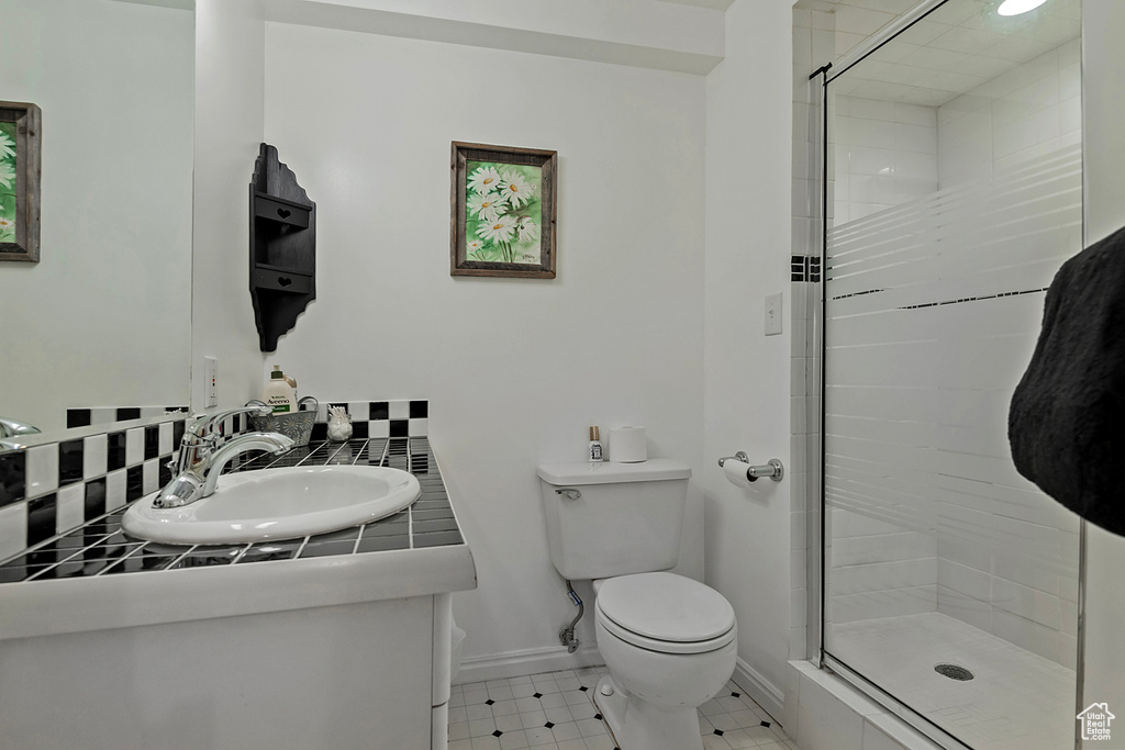 Bathroom featuring toilet, vanity, a shower stall, and decorative backsplash