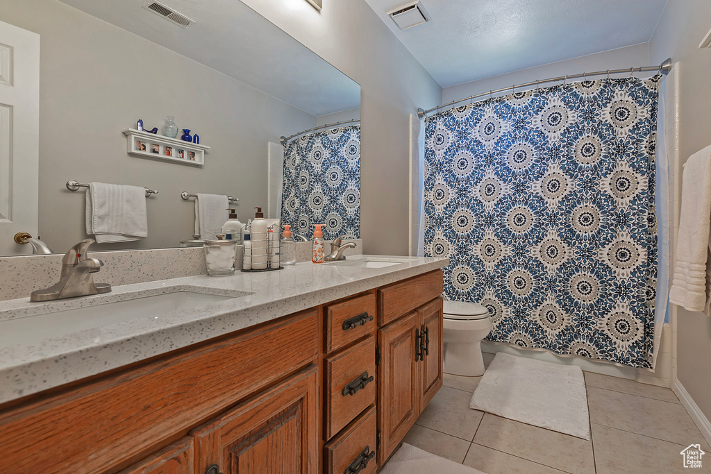 Bathroom featuring tile patterned flooring, double vanity, toilet, and a shower with curtain