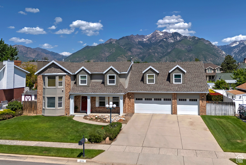 View of front facade with brick siding, concrete driveway, a mountain view, and roof with shingles