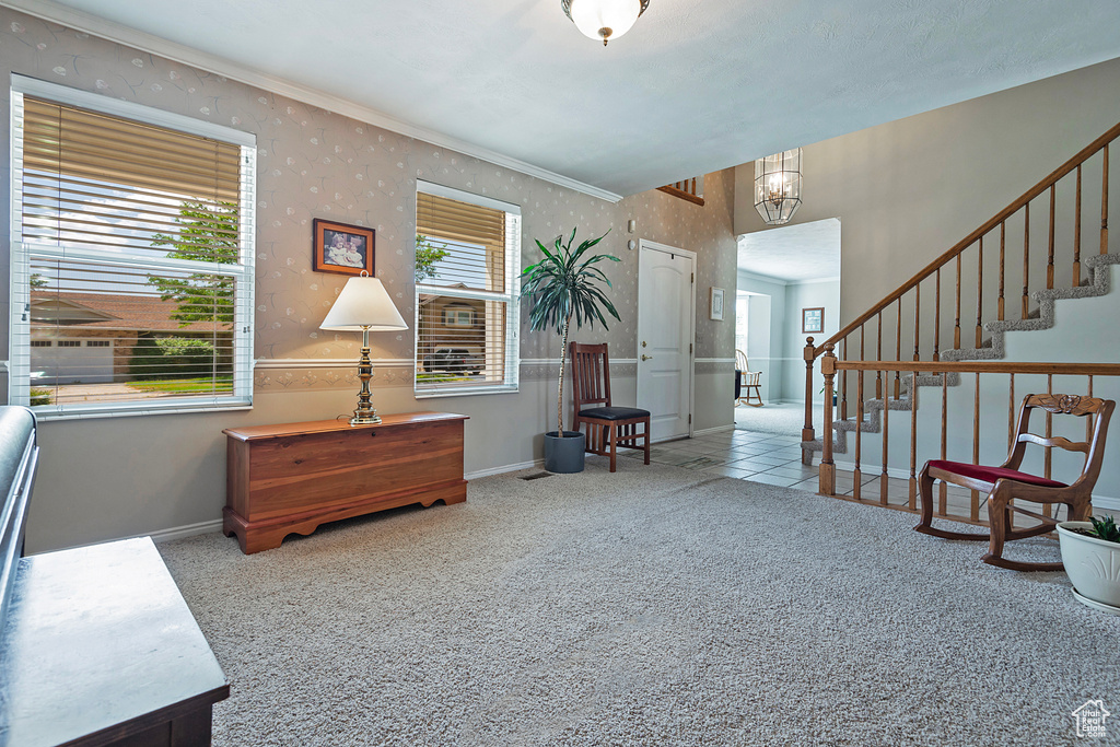 Living area with carpet floors, baseboards, a chandelier, stairway, and crown molding