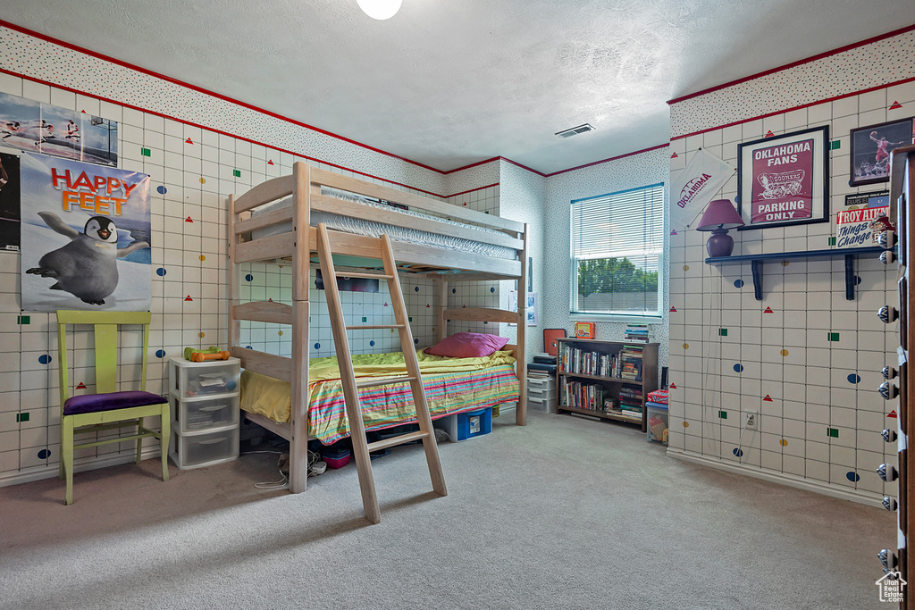 Bedroom with carpet, wallpapered walls, and a textured ceiling