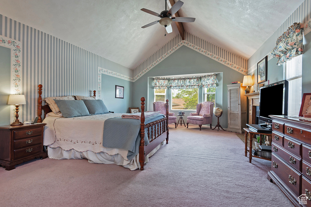 Carpeted bedroom featuring lofted ceiling, wallpapered walls, and a ceiling fan