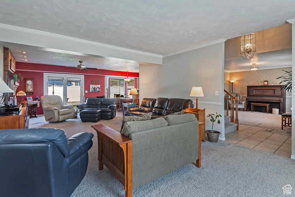 Living area with carpet floors, stairs, ornamental molding, ceiling fan, and a chandelier