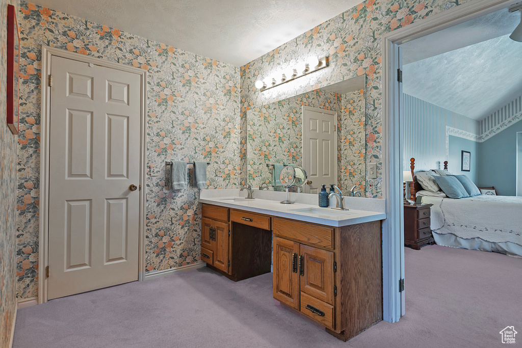 Full bath featuring ensuite bath, wallpapered walls, double vanity, and baseboards