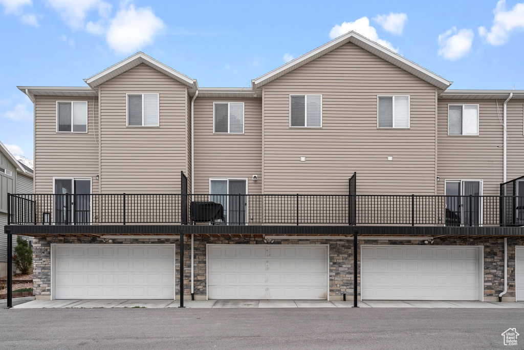 Back of house featuring a garage and stone siding