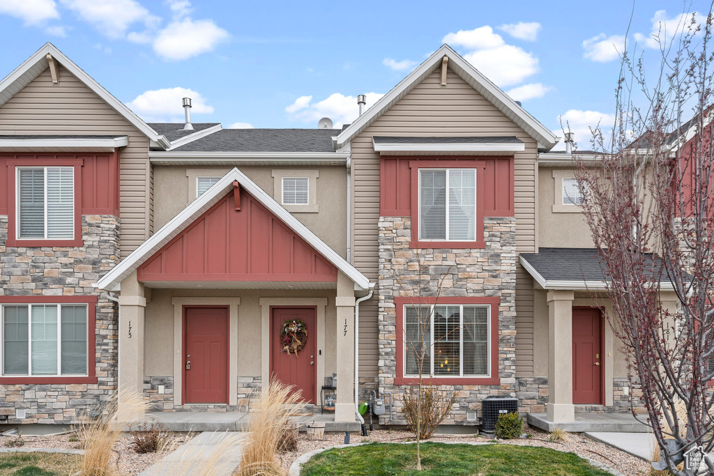 Multi unit property featuring stone siding, stucco siding, central AC unit, and roof with shingles
