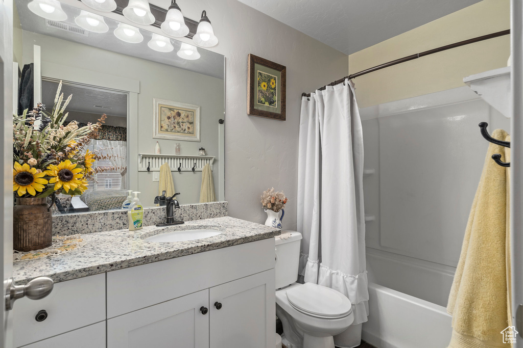 Full bathroom with vanity, shower / bath combo with shower curtain, and toilet