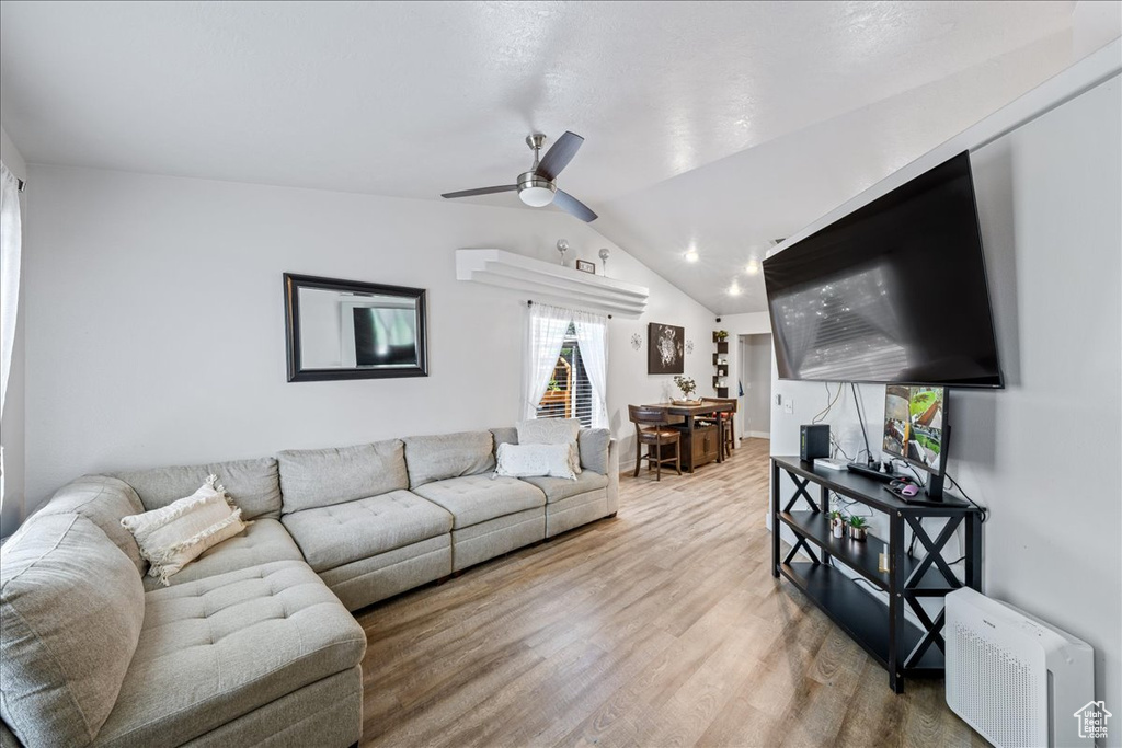 Living area featuring light wood-type flooring, a ceiling fan, and vaulted ceiling