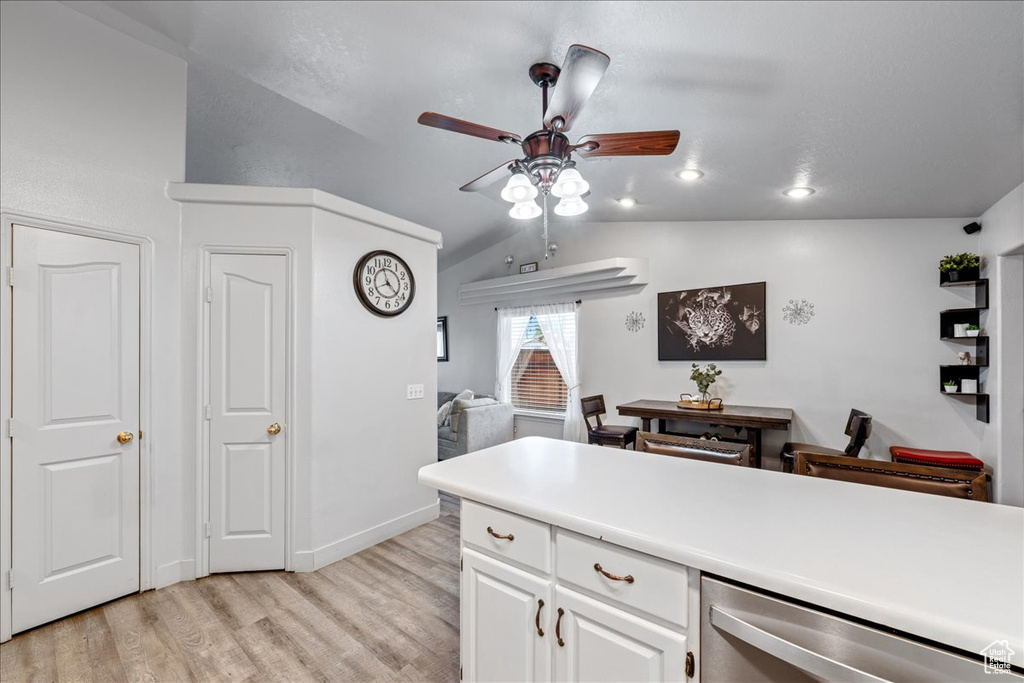Kitchen featuring dishwasher, light wood-type flooring, a ceiling fan, vaulted ceiling, and white cabinets