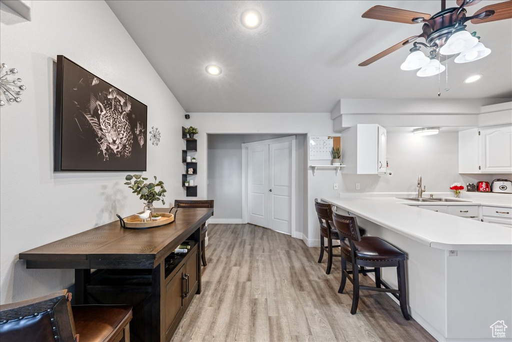 Kitchen featuring a sink, light wood-type flooring, a ceiling fan, light countertops, and white cabinetry
