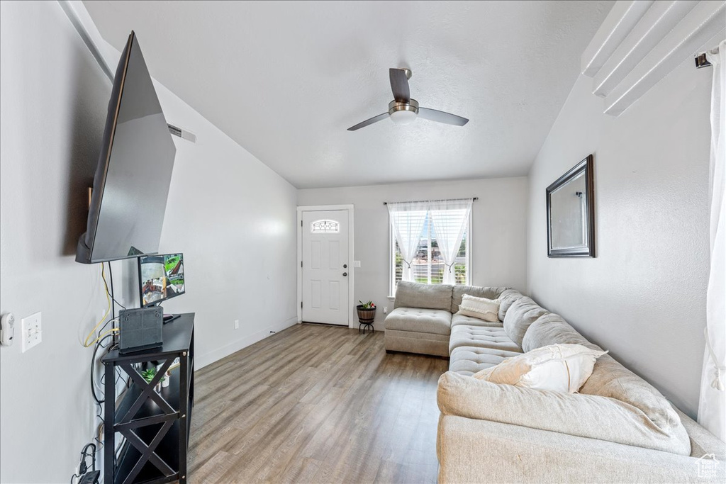 Living area with a ceiling fan, wood finished floors, and baseboards