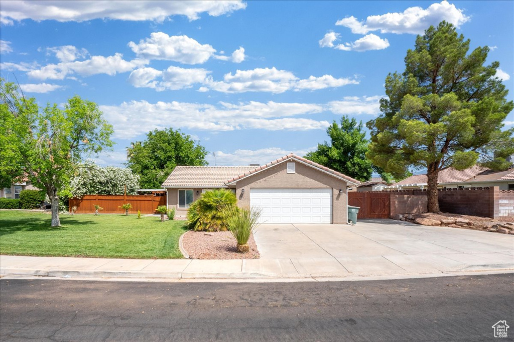 Ranch-style home with a garage, a tiled roof, concrete driveway, and stucco siding