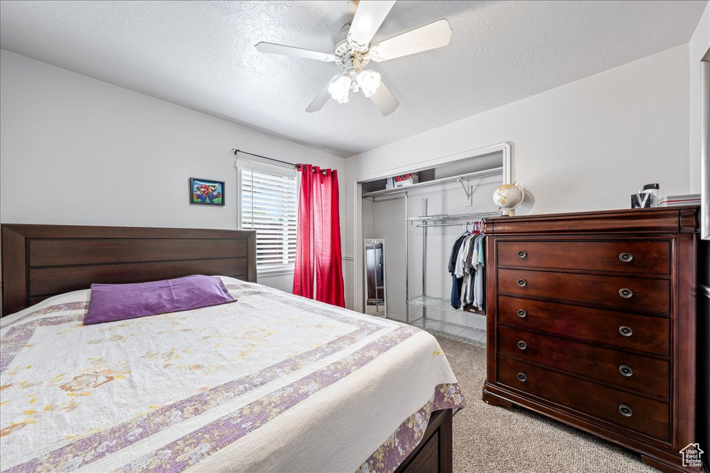 Bedroom featuring a closet, light carpet, ceiling fan, and a textured ceiling