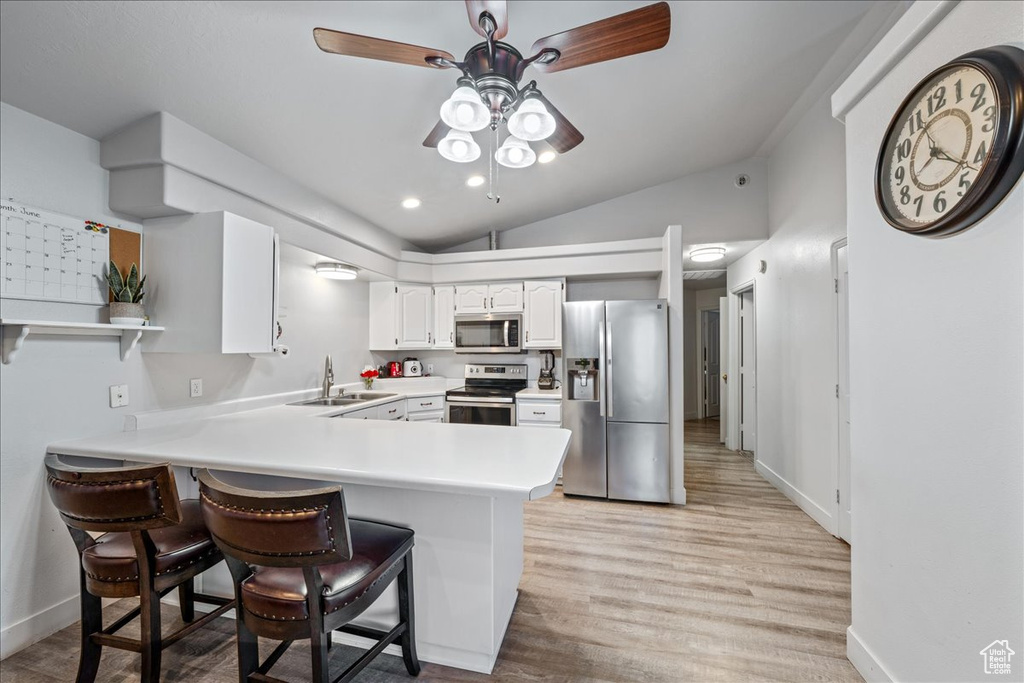 Kitchen with stainless steel appliances, a sink, ceiling fan, a peninsula, and vaulted ceiling