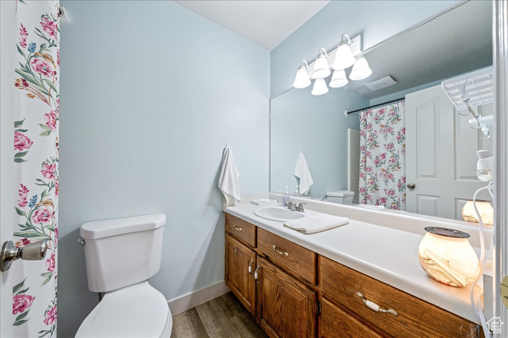 Full bathroom featuring toilet, vanity, wood finished floors, baseboards, and a shower with shower curtain