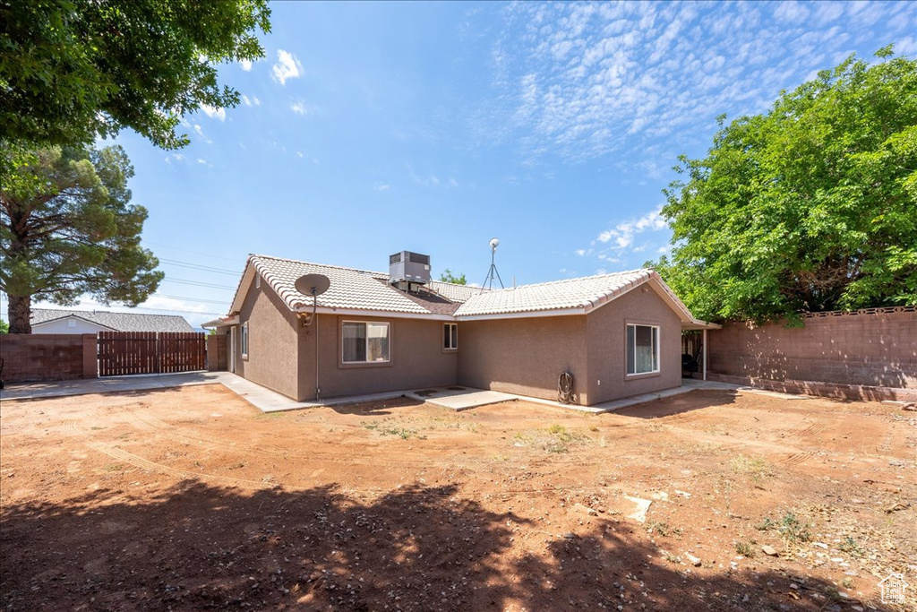 Rear view of property with a tile roof, stucco siding, a fenced backyard, a patio, and central AC
