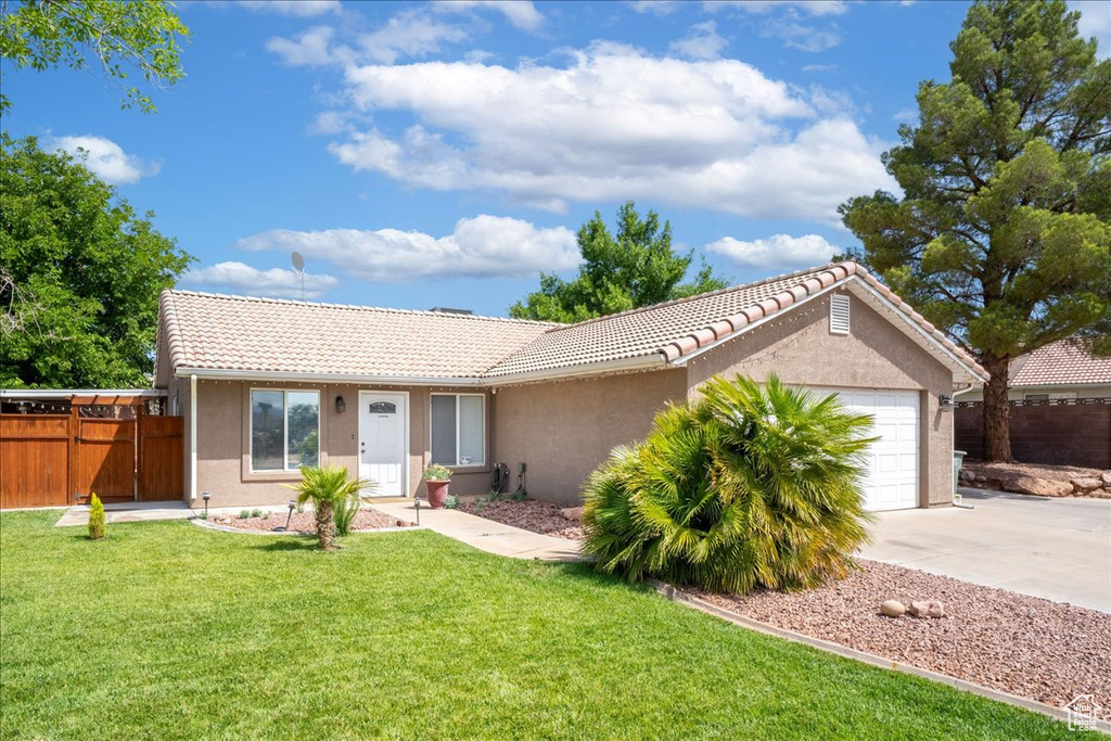 Ranch-style home featuring concrete driveway, an attached garage, stucco siding, and a tiled roof