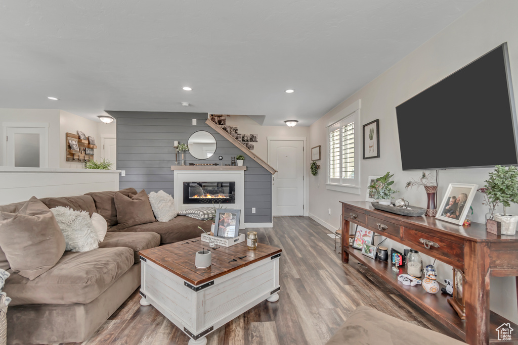 Living area featuring wood finished floors, a glass covered fireplace, recessed lighting, and baseboards
