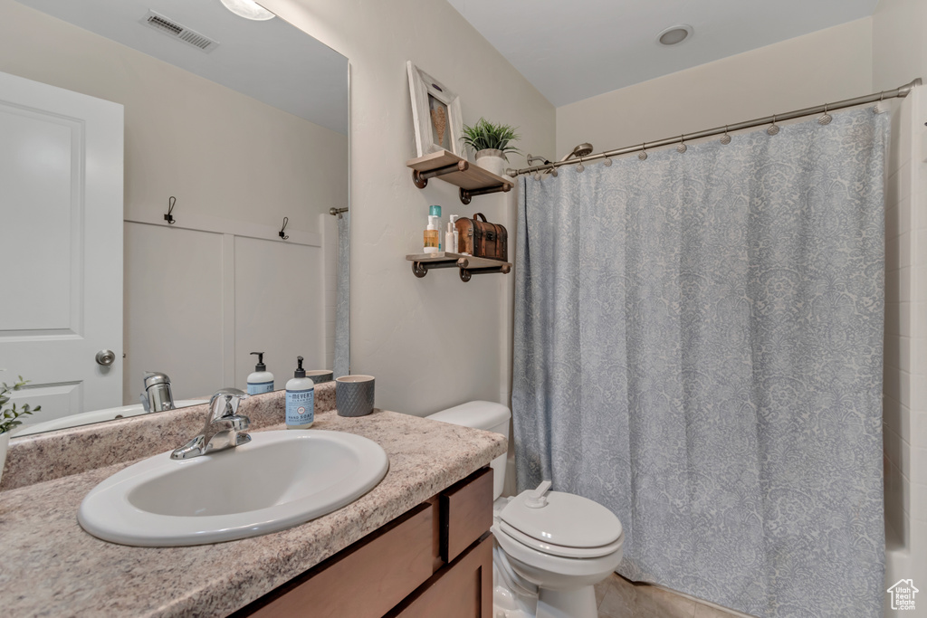 Full bathroom with vanity, toilet, and curtained shower