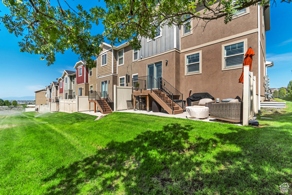 Back of house featuring stairway, stucco siding, a residential view, and a lawn