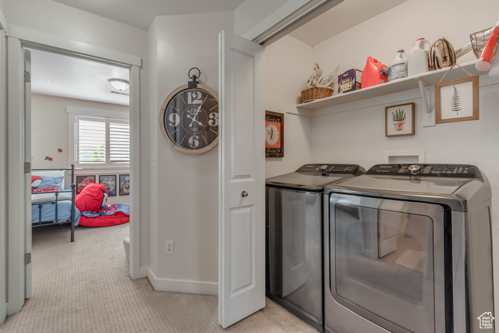 Laundry room with washer and dryer, light carpet, and baseboards