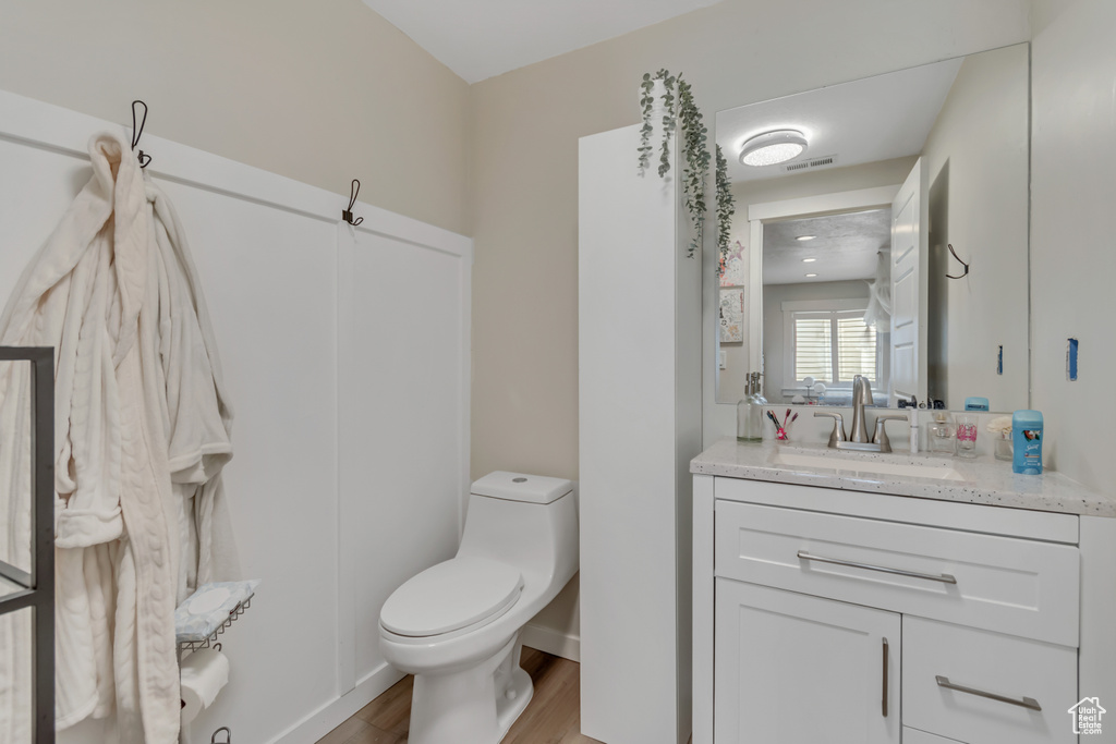 Half bath with toilet, wood finished floors, and vanity
