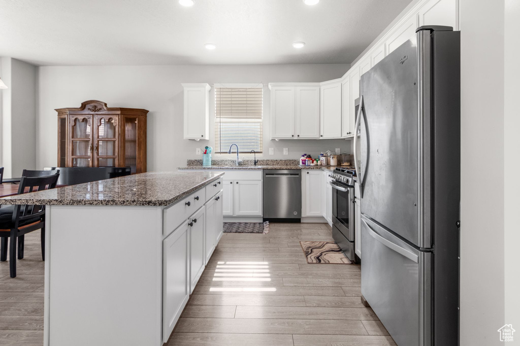 Kitchen with stainless steel appliances, recessed lighting, light wood-style flooring, a kitchen island, and white cabinetry