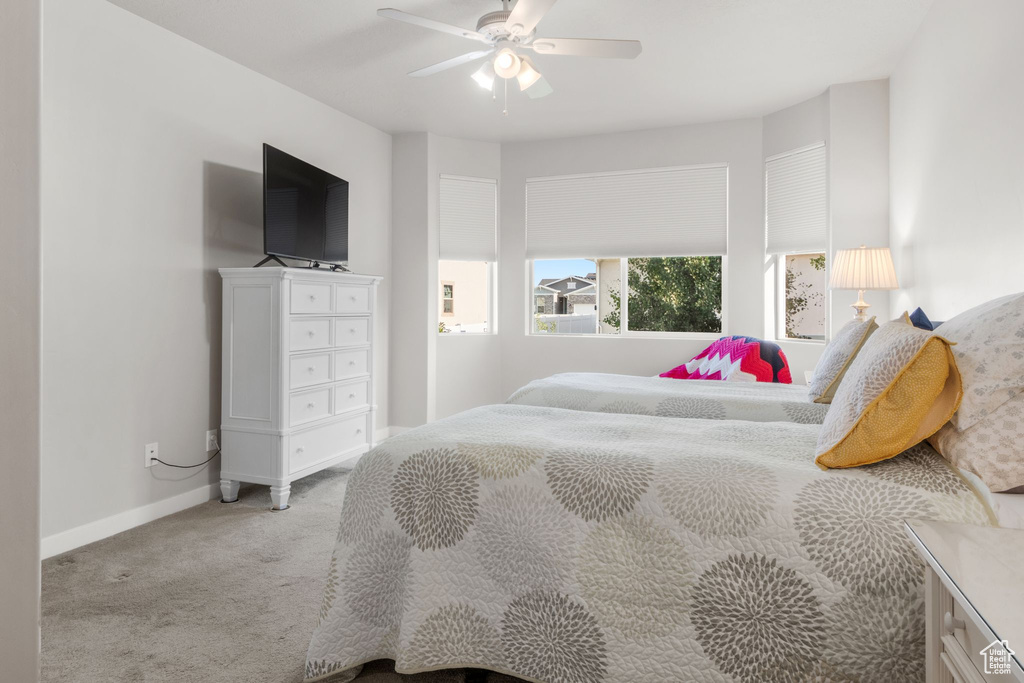 Bedroom with light carpet, baseboards, and a ceiling fan
