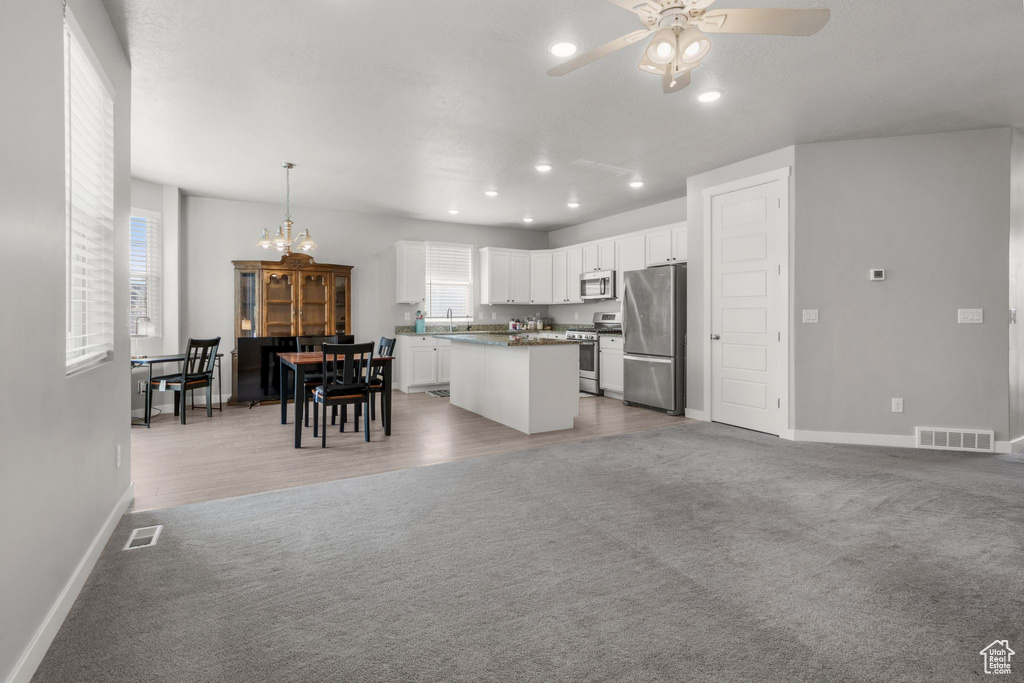 Kitchen featuring appliances with stainless steel finishes, light carpet, a ceiling fan, baseboards, and white cabinetry