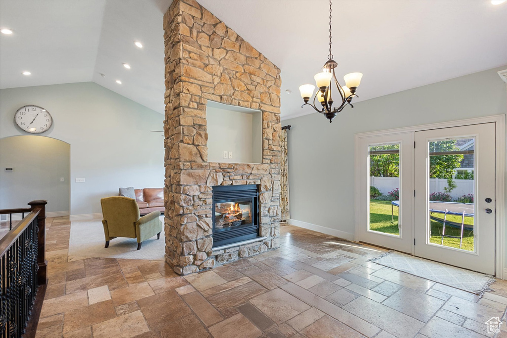 Living room with stone tile flooring, a chandelier, a stone fireplace, baseboards, and recessed lighting