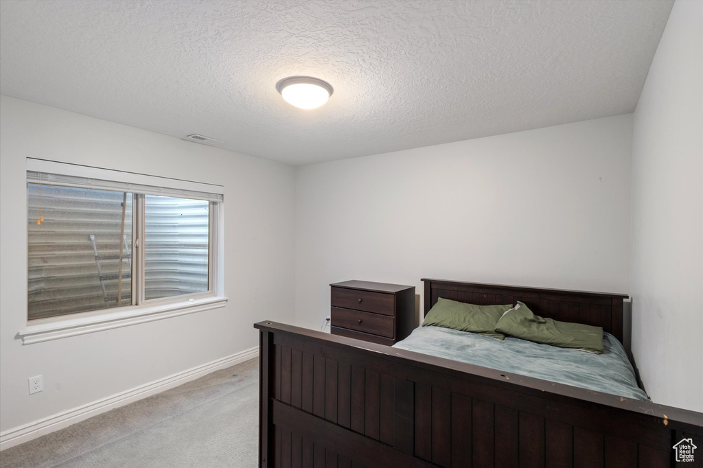 Bedroom featuring light colored carpet, a textured ceiling, and baseboards