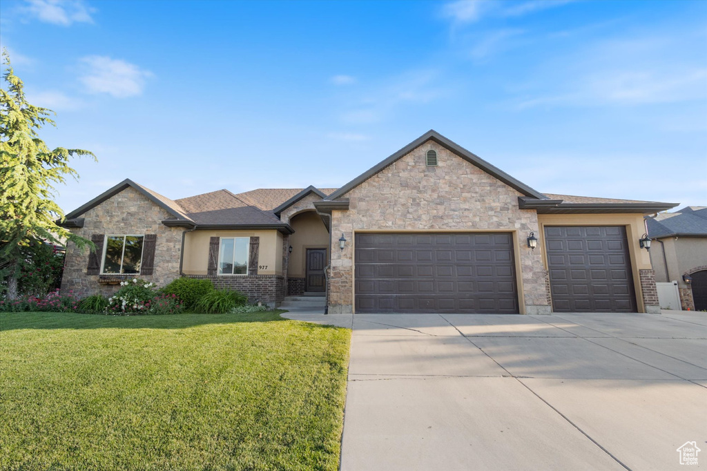 View of front of property with an attached garage, concrete driveway, a front lawn, and stucco siding