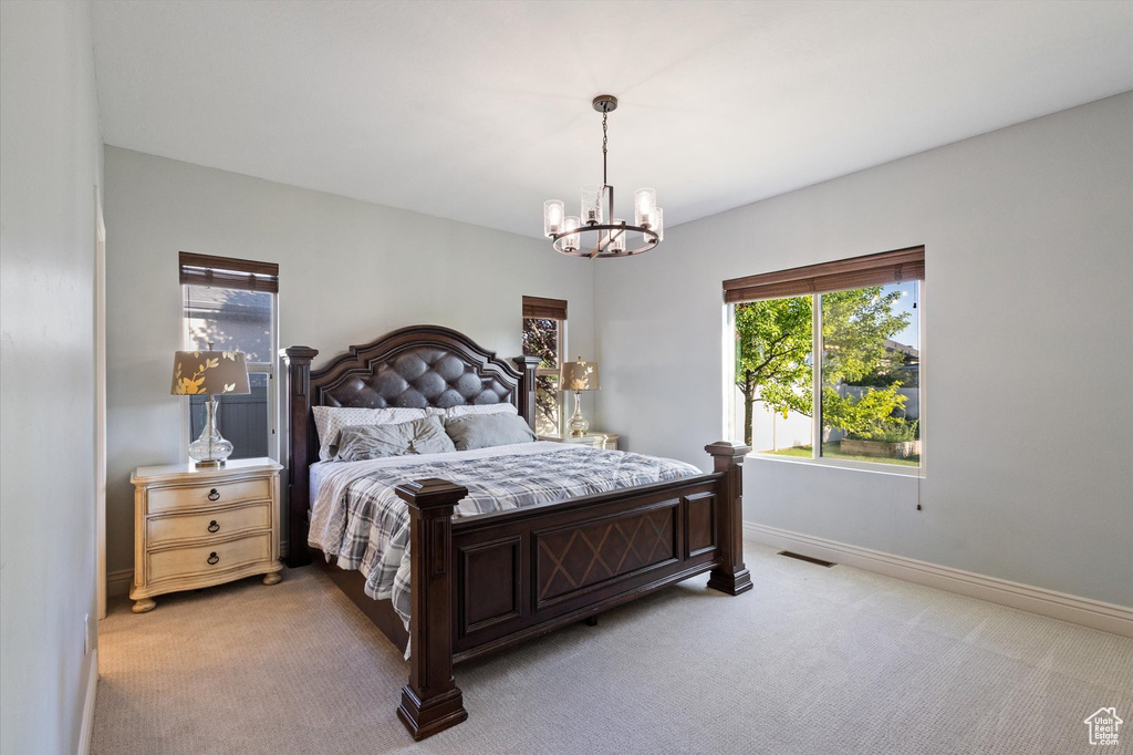 Bedroom featuring multiple windows, a chandelier, and light colored carpet