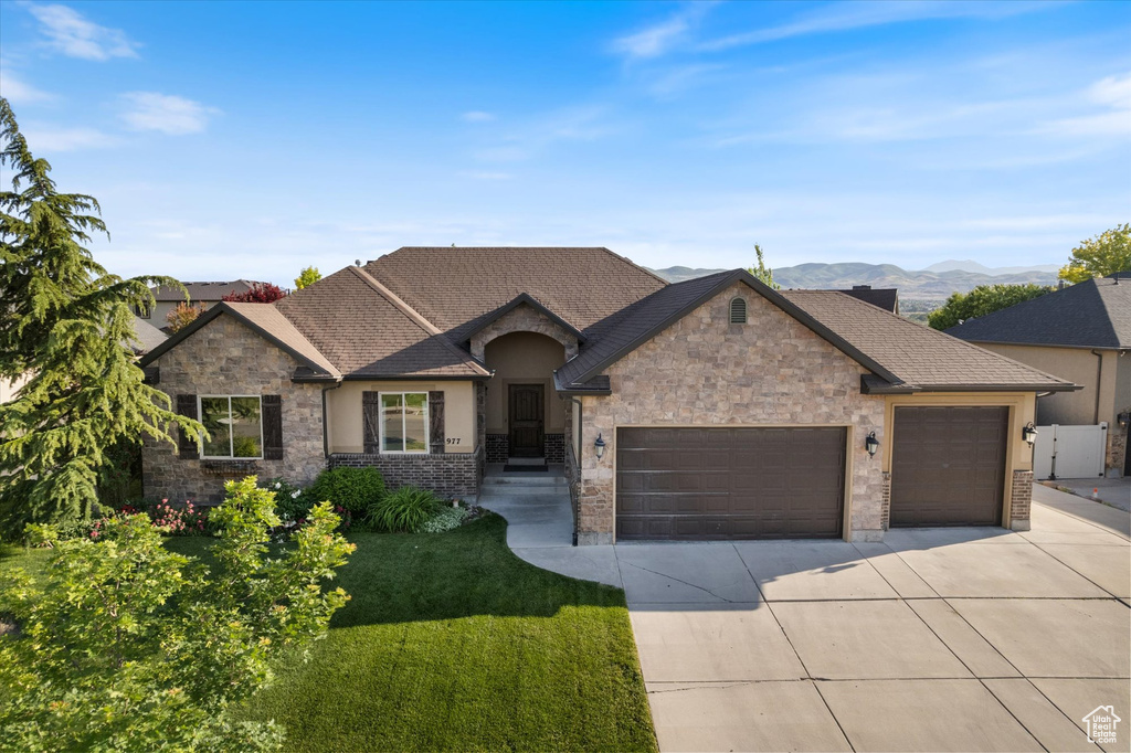 French country style house with a garage, driveway, a front lawn, stucco siding, and stone siding