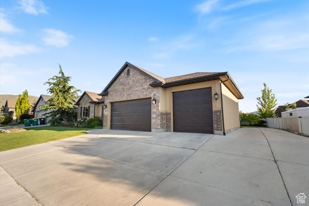 View of front of house with driveway, a garage, and stone siding