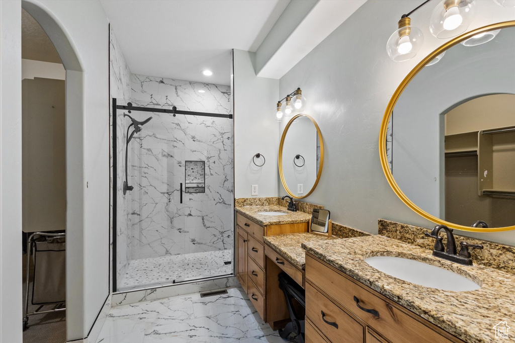 Full bath with marble look tile flooring, a marble finish shower, recessed lighting, vanity, and a spacious closet