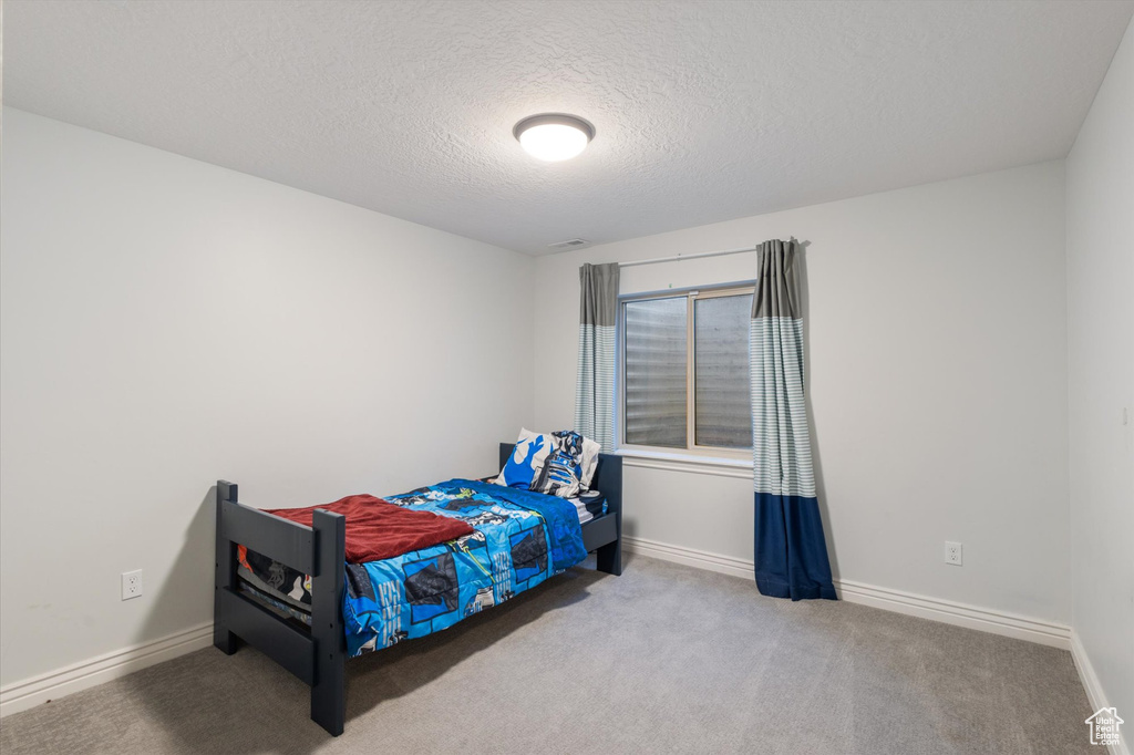 Carpeted bedroom featuring a textured ceiling and baseboards