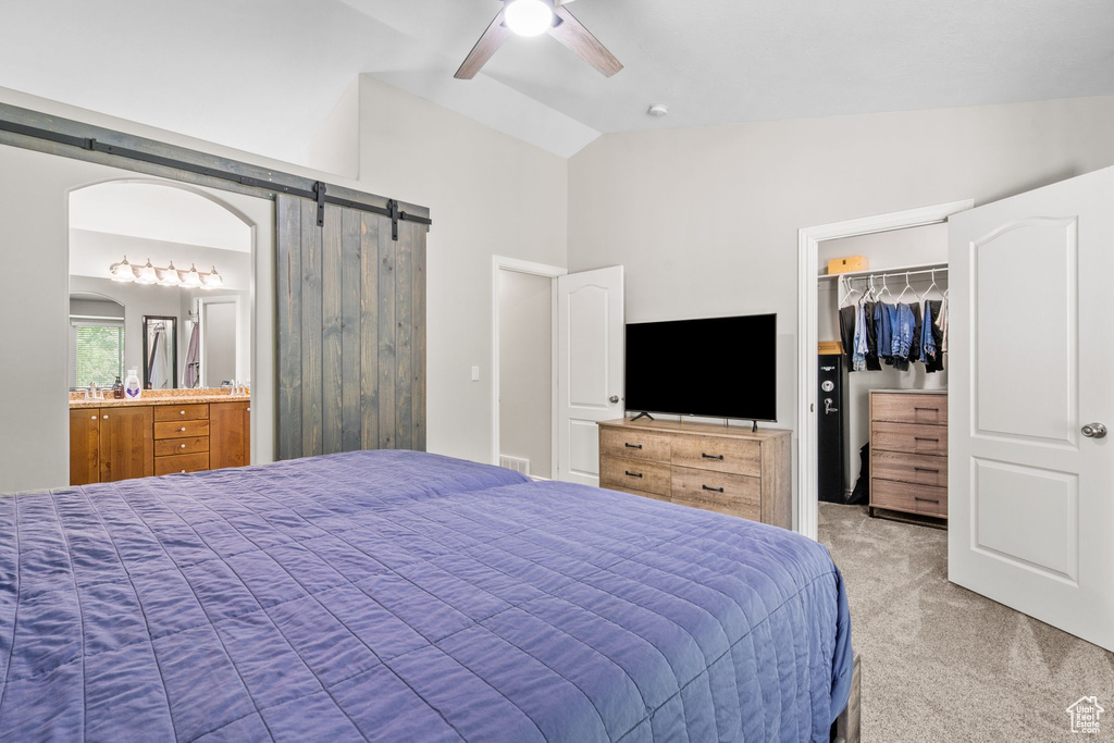 Bedroom featuring light carpet, lofted ceiling, a spacious closet, a barn door, and a closet