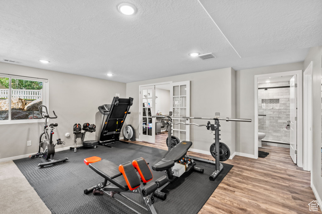 Workout room with a textured ceiling, baseboards, recessed lighting, wood finished floors, and french doors