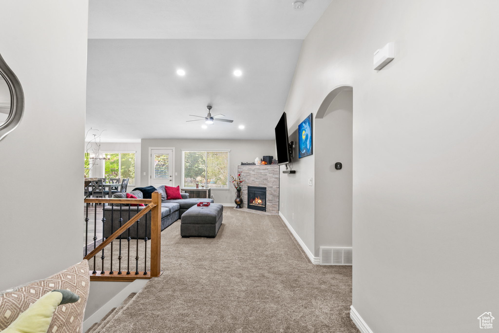 Living area featuring carpet flooring, a stone fireplace, baseboards, ceiling fan, and recessed lighting