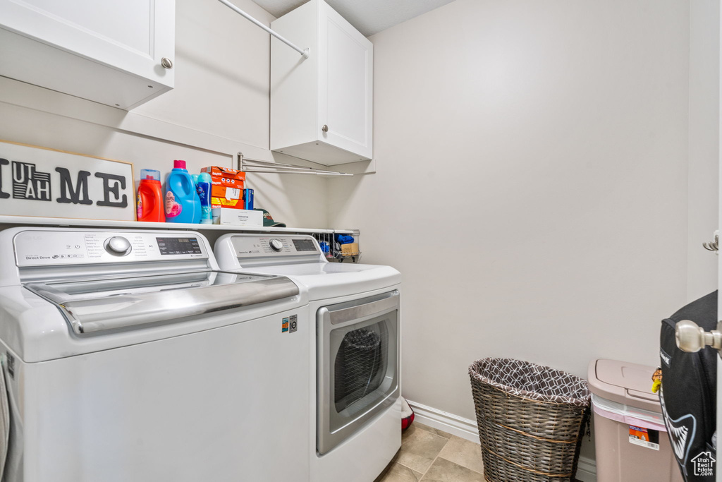 Washroom featuring cabinet space, washing machine and clothes dryer, and baseboards