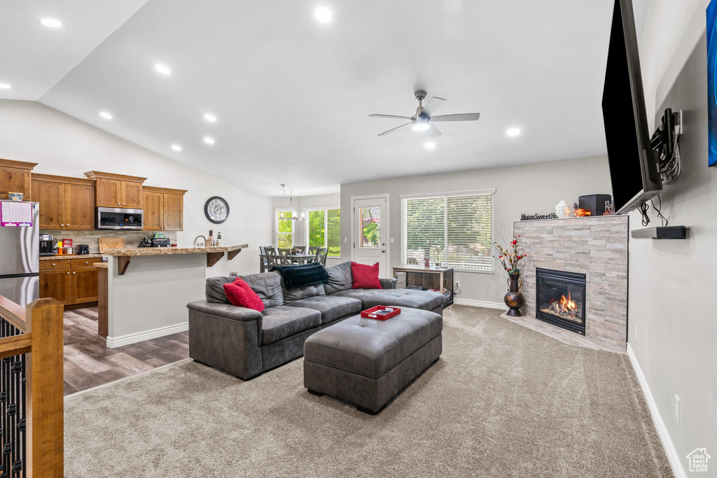 Living room with recessed lighting, a ceiling fan, a stone fireplace, baseboards, and vaulted ceiling