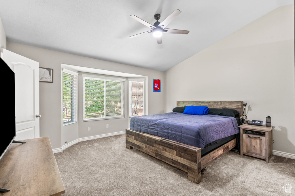 Bedroom with light carpet, vaulted ceiling, baseboards, and a ceiling fan