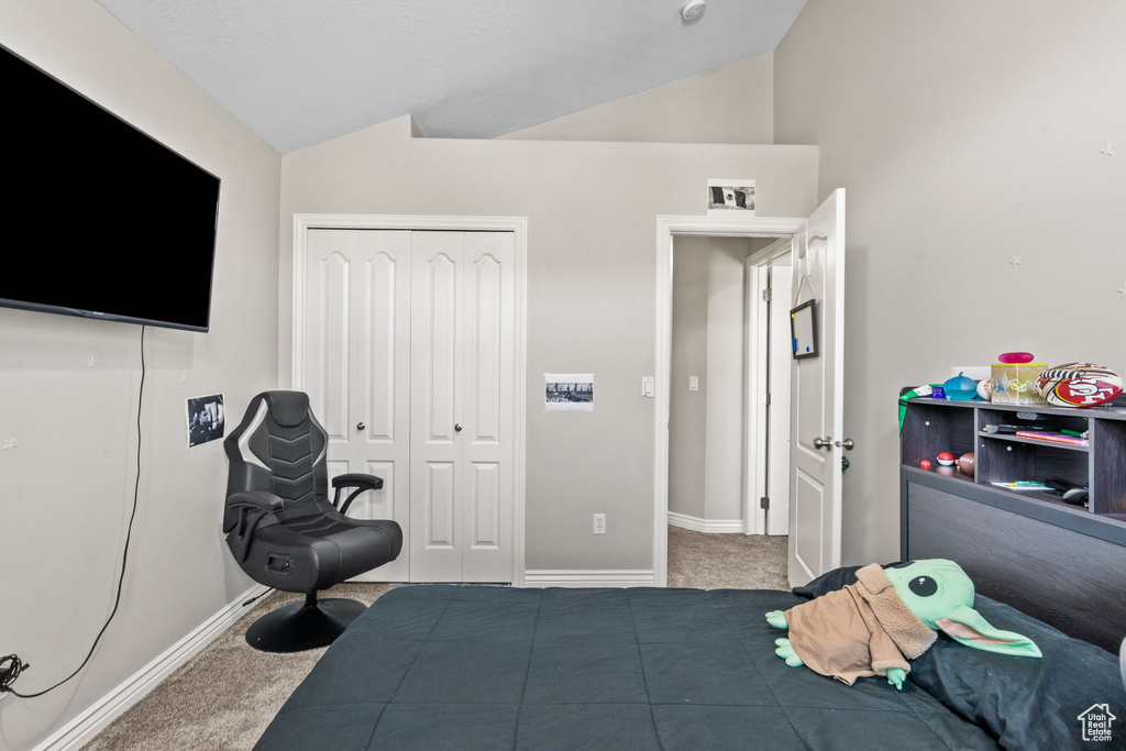 Carpeted bedroom featuring vaulted ceiling, a closet, and baseboards
