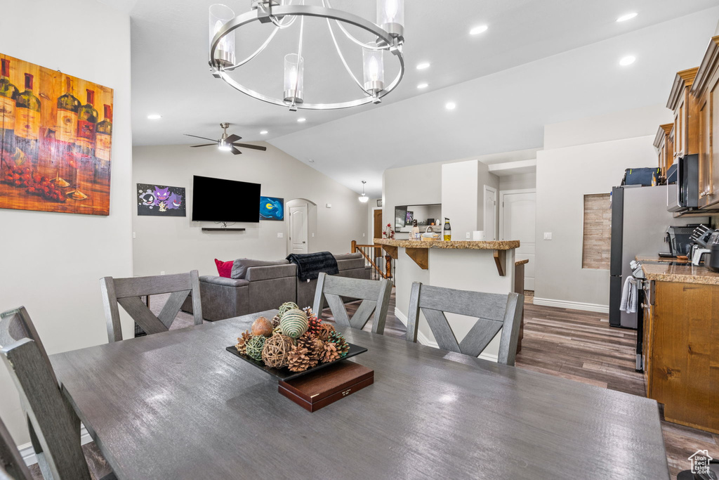 Dining space with lofted ceiling, dark wood-style flooring, ceiling fan, a chandelier, and recessed lighting
