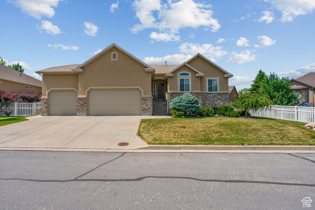 View of front of property with stucco siding, a garage, driveway, and stone siding