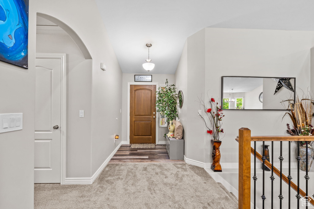 Carpeted foyer with arched walkways and baseboards