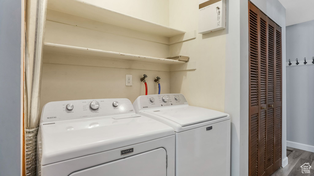 Laundry room featuring washer and clothes dryer, wood finished floors, and baseboards