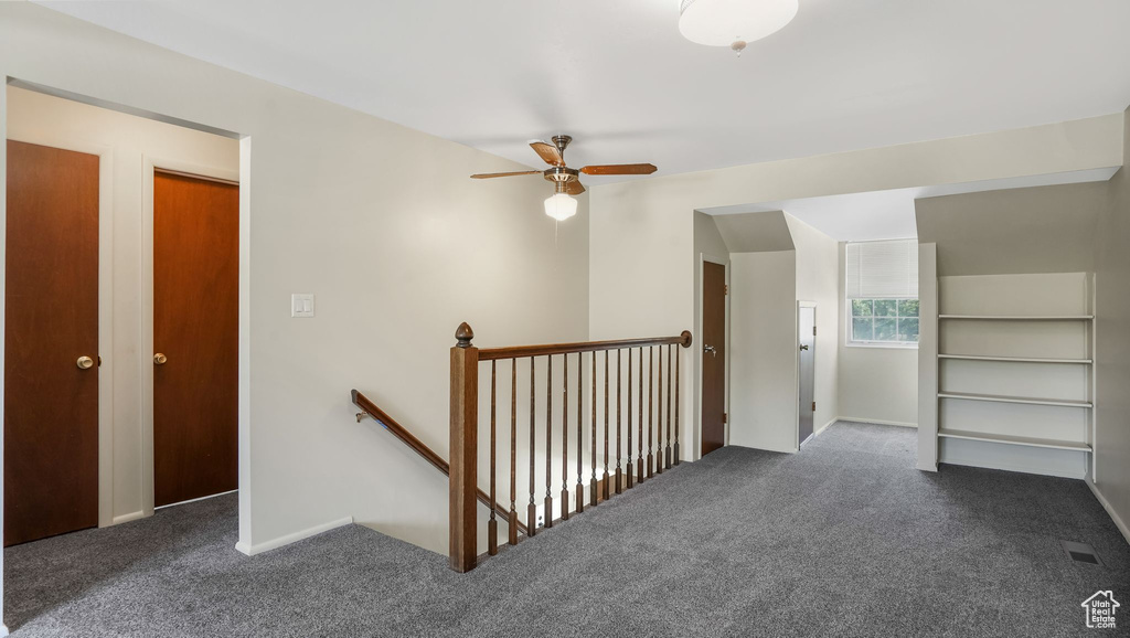 Hallway featuring an upstairs landing and dark carpet